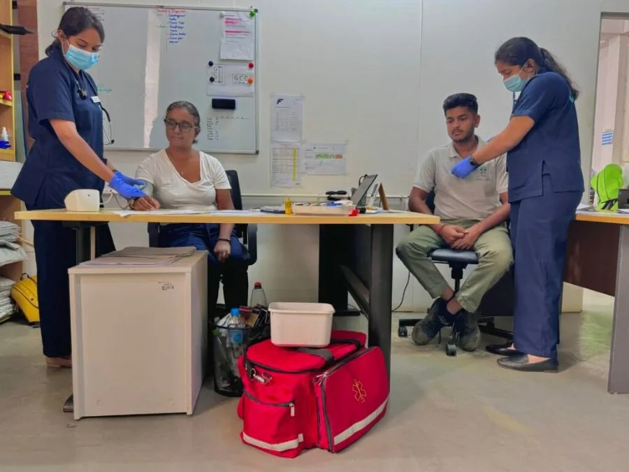 Two nurses checking workers' blood pressure during a workplace visit.